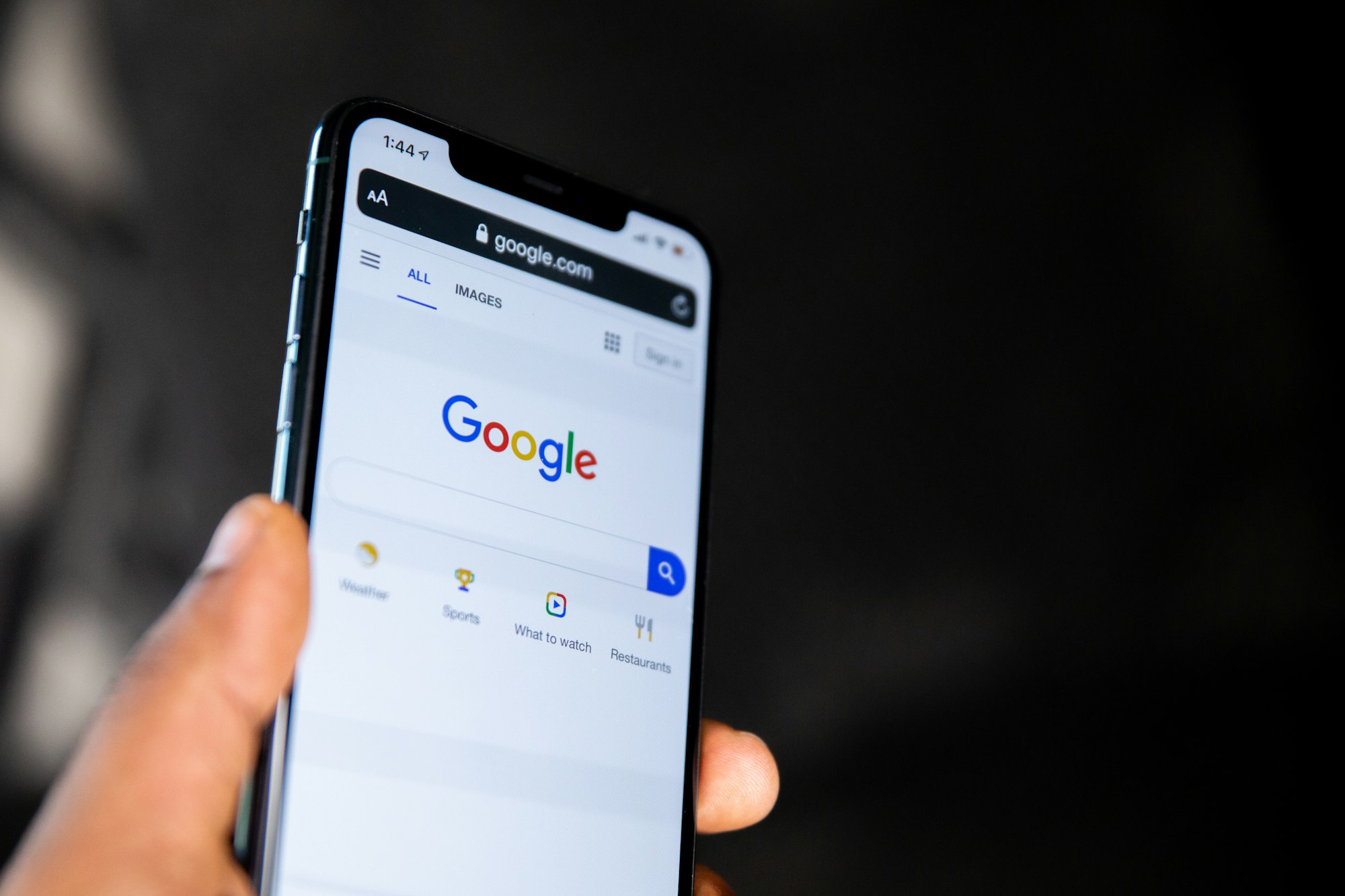 Hand holding a smartphone with Google search open