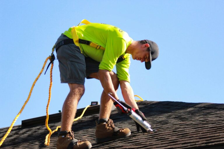Roofer in a lime shirt working on a roof under a clear sky